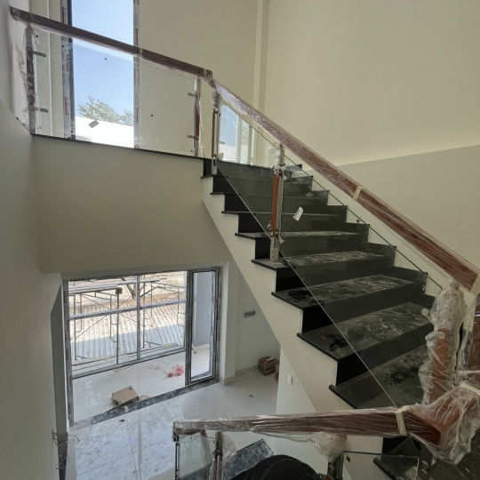 Cầu thang kính tay vịn gỗ có trụ